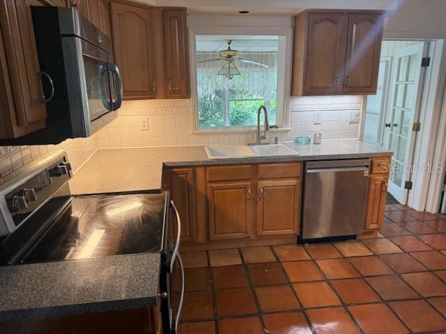 2451 Loma Linda St, Sarasota, FL 34239 - kitchen featuring stainless steel appliances, decorative backsplash, a ceiling fan, and tile patterned floors