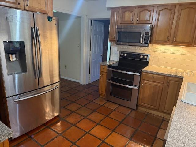 2451 Loma Linda St, Sarasota, FL 34239 - kitchen with stainless steel appliances, backsplash, and brown cabinets