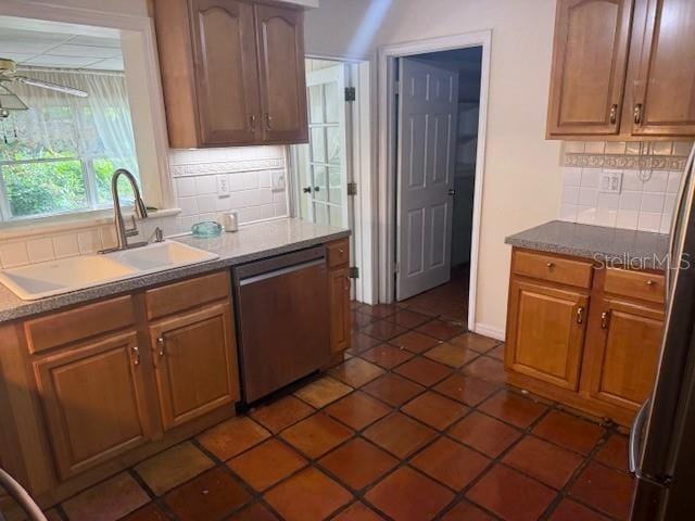 2451 Loma Linda St, Sarasota, FL 34239 - kitchen with stainless steel dishwasher, backsplash, dark tile patterned flooring, and brown cabinetry