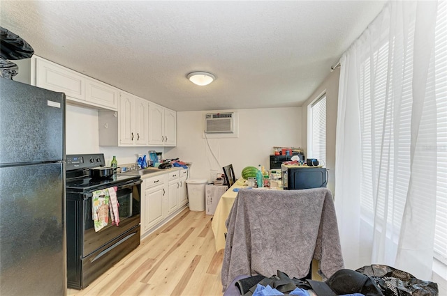 1701 13th St W, Bradenton, FL 34205 - kitchen with black appliances, light wood finished floors, white cabinets, an AC wall unit, and a textured ceiling
