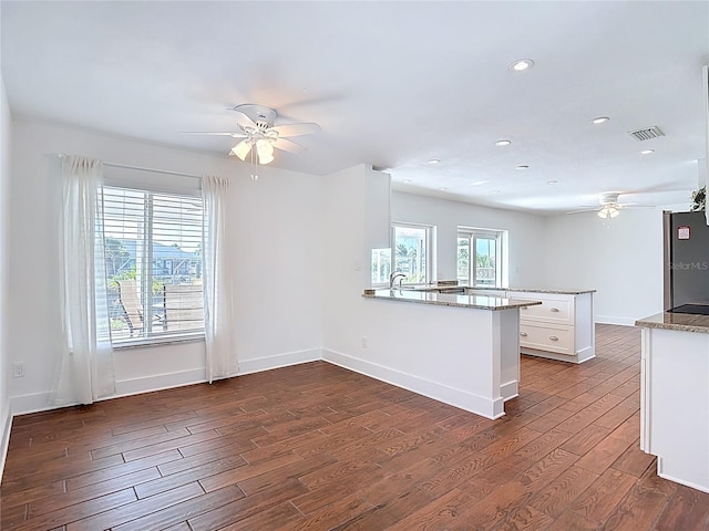 6341 Cocoa Ln, Apollo Beach, FL 33572 - kitchen featuring ceiling fan, a peninsula, freestanding refrigerator, dark wood-style flooring, and white cabinetry