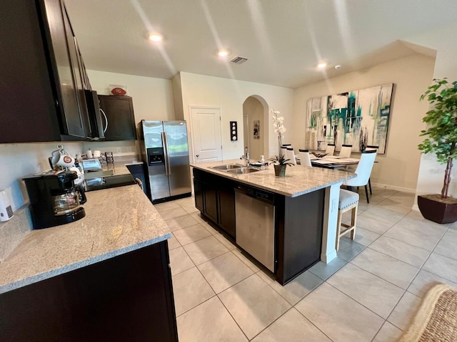 8995 Milestone Dr, Sarasota, FL 34238 - kitchen featuring stainless steel appliances, arched walkways, a breakfast bar area, a center island with sink, and light tile patterned floors