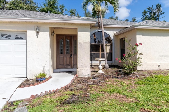 4805 Cypress Lake Ct, Sarasota, FL 34243 - view of exterior entry with stucco siding, roof with shingles, and a garage