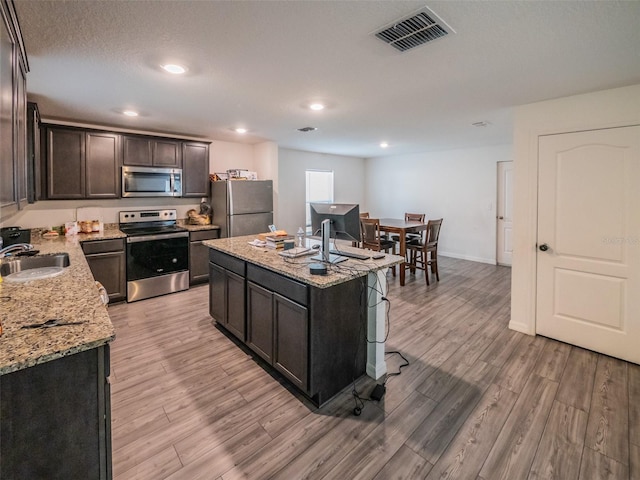 938 Mansfield Rd, Tavares, FL 32778 - kitchen featuring stainless steel appliances, light wood-style floors, a kitchen island, light stone counters, and recessed lighting