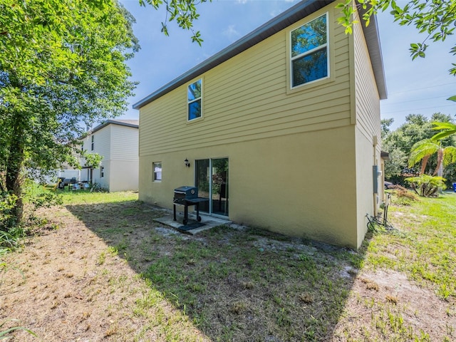 938 Mansfield Rd, Tavares, FL 32778 - back of house with stucco siding, a lawn, and a patio