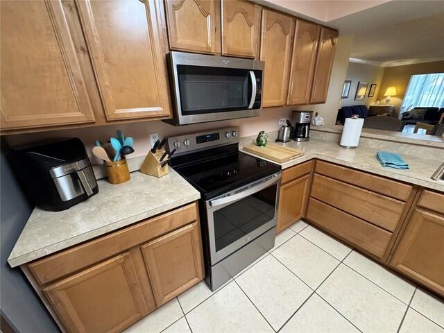 3810 75th St W Unit 137, Bradenton, FL 34209 - kitchen featuring appliances with stainless steel finishes, light countertops, light tile patterned flooring, crown molding, and open floor plan
