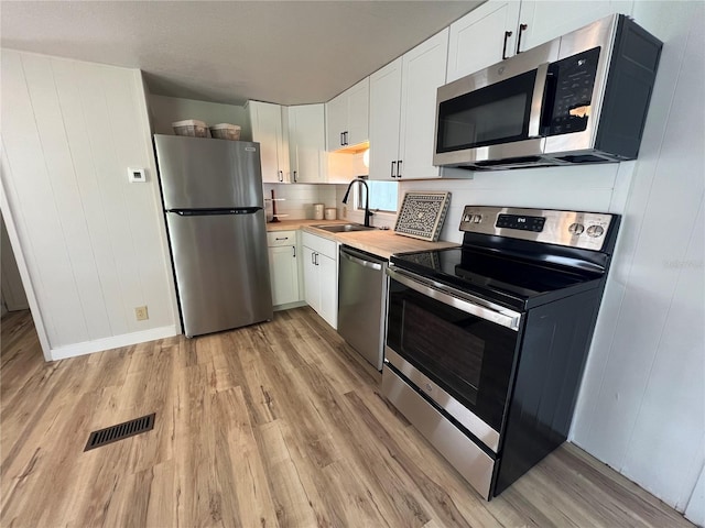 1871 Palm Springs St, Sarasota, FL 34234 - kitchen with stainless steel appliances, light wood finished floors, white cabinets, and butcher block countertops