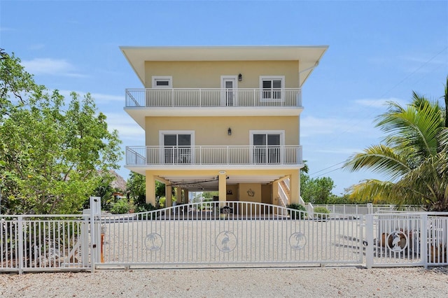 830 Egret Ln, Key Largo, FL 33037 - beach home featuring a balcony, a fenced front yard, a gate, a carport, and stucco siding