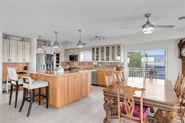 830 Egret Ln, Key Largo, FL 33037 - kitchen featuring stainless steel appliances, tasteful backsplash, a ceiling fan, glass insert cabinets, and a kitchen island with sink