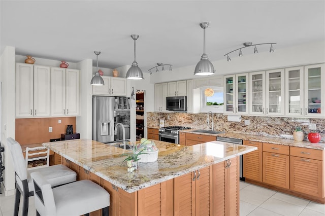 830 Egret Ln, Key Largo, FL 33037 - kitchen featuring stainless steel appliances, backsplash, glass insert cabinets, a kitchen island with sink, and a kitchen bar