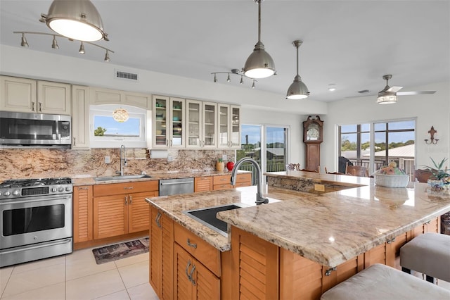 830 Egret Ln, Key Largo, FL 33037 - kitchen with appliances with stainless steel finishes, backsplash, light tile patterned flooring, a kitchen breakfast bar, and light stone countertops