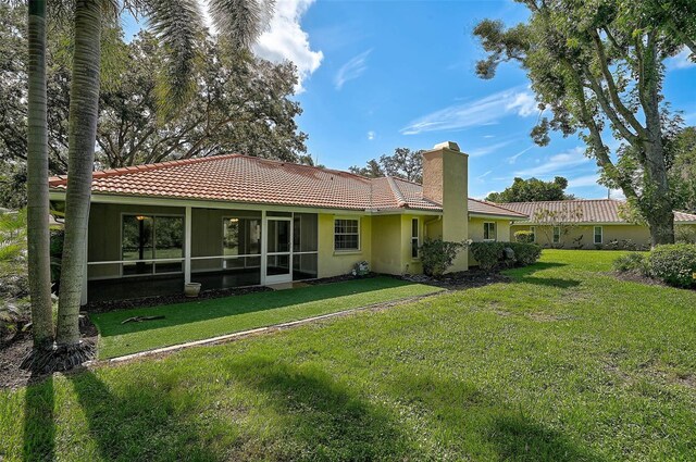1674 Cottonwood Trl, Sarasota, FL 34232 - rear view of house with a tile roof, a chimney, stucco siding, and a lawn