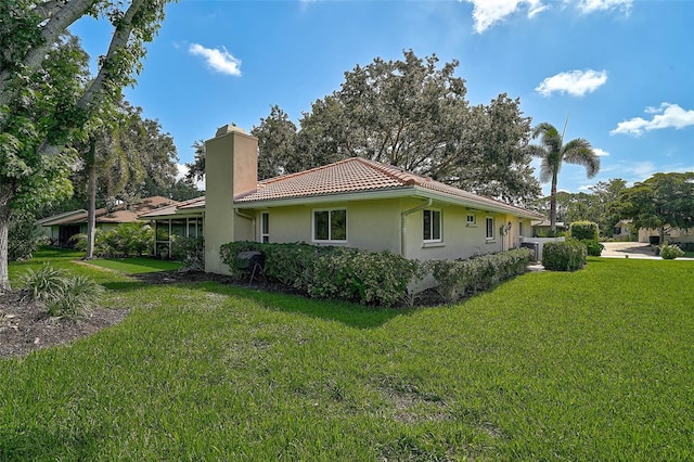 1674 Cottonwood Trl, Sarasota, FL 34232 - view of side of home featuring a chimney, a lawn, a tiled roof, and stucco siding