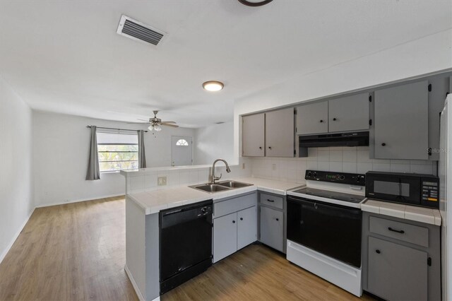 4508 101st St W Unit A, Bradenton, FL 34210 - kitchen featuring black appliances, gray cabinetry, a peninsula, backsplash, and tile countertops