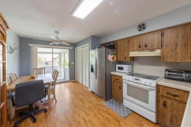 4508 101st St W Unit A, Bradenton, FL 34210 - kitchen with white appliances, under cabinet range hood, brown cabinets, and tile countertops