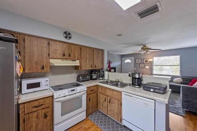 4508 101st St W Unit A, Bradenton, FL 34210 - kitchen featuring white appliances, under cabinet range hood, a peninsula, open floor plan, and tile counters