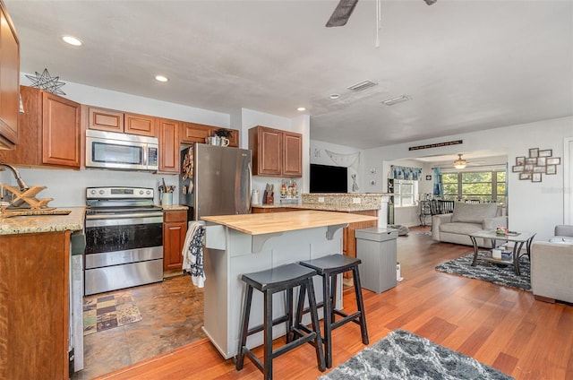 4481 Lagg Ave, Fort Myers, FL 33901 - kitchen with appliances with stainless steel finishes, ceiling fan, open floor plan, a breakfast bar area, and brown cabinetry