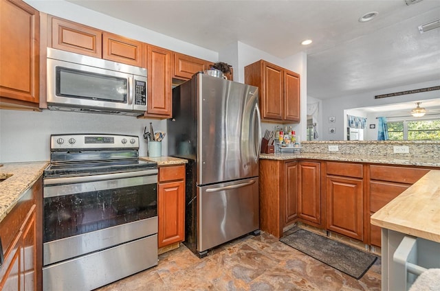 4481 Lagg Ave, Fort Myers, FL 33901 - kitchen featuring appliances with stainless steel finishes, brown cabinets, light stone countertops, and recessed lighting