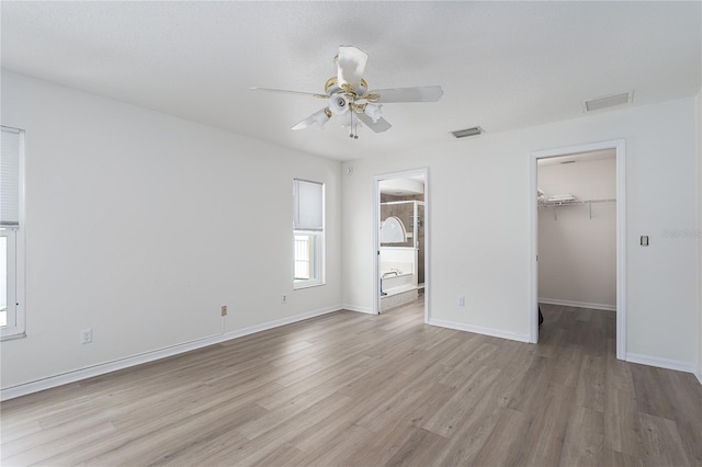 6114 68th Dr E, Palmetto, FL 34221 - unfurnished bedroom with a walk in closet, wood finished floors, a closet, ensuite bath, and a ceiling fan
