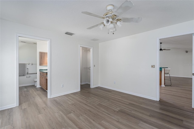 6114 68th Dr E, Palmetto, FL 34221 - unfurnished bedroom featuring wood finished floors, a spacious closet, connected bathroom, ceiling fan, and a closet