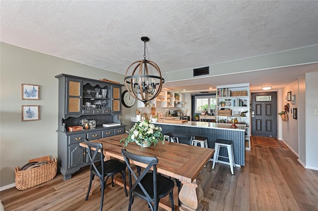 1510 1st Ave W Unit 102, Bradenton, FL 34205 - dining area featuring a chandelier, wood finished floors, and a textured ceiling