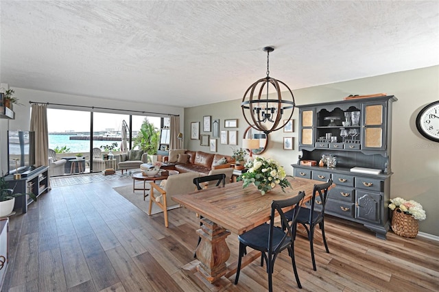 1510 1st Ave W Unit 102, Bradenton, FL 34205 - dining area featuring a chandelier, a textured ceiling, and wood finished floors