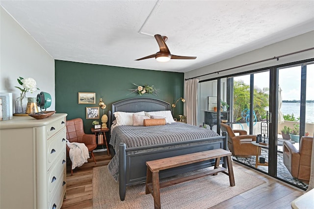1510 1st Ave W Unit 102, Bradenton, FL 34205 - bedroom with access to exterior, light wood-style floors, an accent wall, a textured ceiling, and a water view