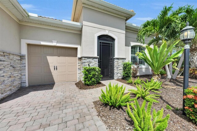 3379 Chestertown Loop, Bradenton, FL 34211 - view of exterior entry featuring stone siding, an attached garage, and stucco siding