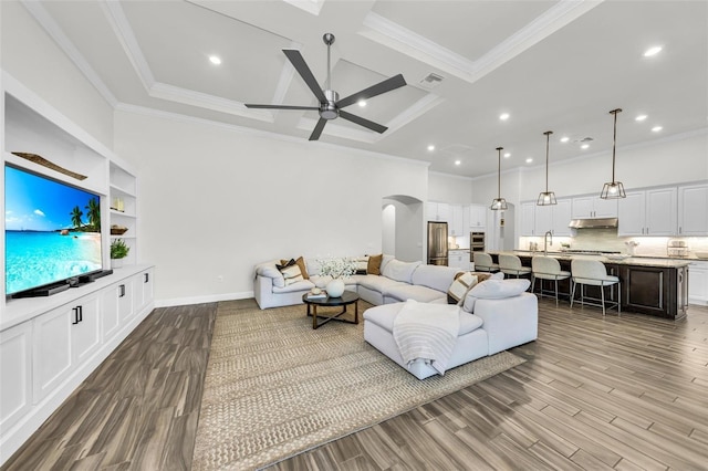 3379 Chestertown Loop, Bradenton, FL 34211 - living area with coffered ceiling, crown molding, arched walkways, a ceiling fan, and wood finished floors