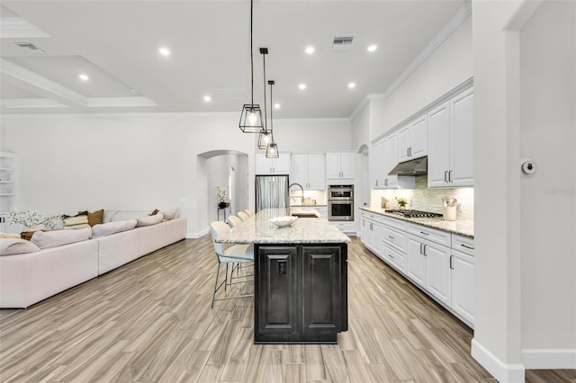 3379 Chestertown Loop, Bradenton, FL 34211 - kitchen featuring under cabinet range hood, arched walkways, open floor plan, a breakfast bar area, and crown molding