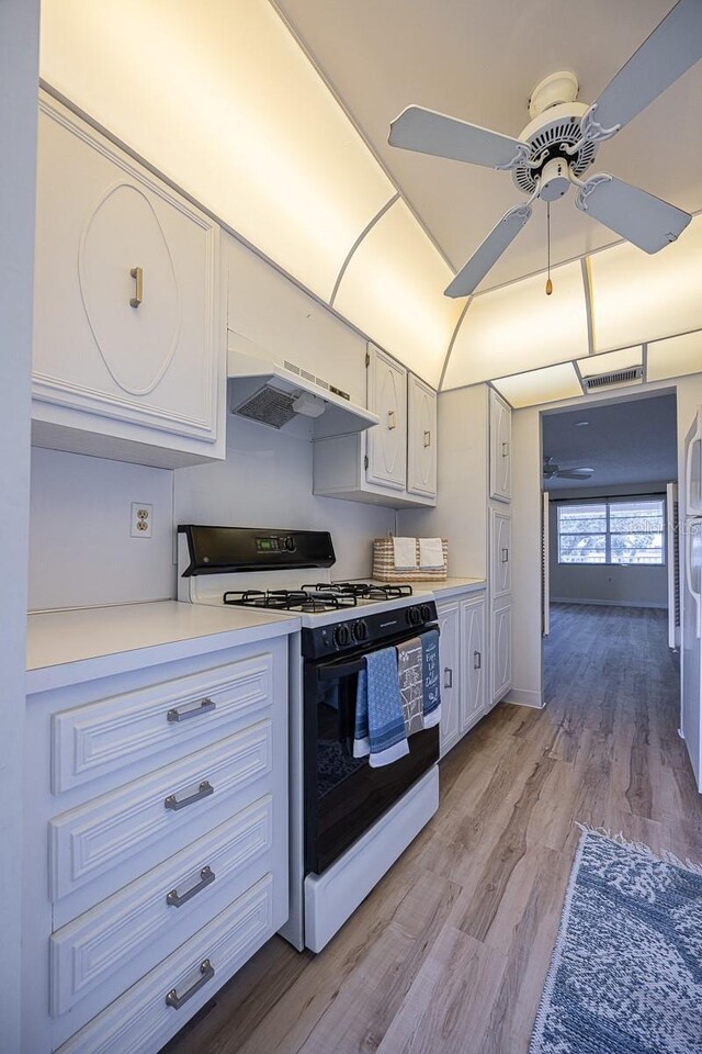 10037 62nd Ter N Unit 23, Saint Petersburg, FL 33708 - kitchen with gas range, premium range hood, ceiling fan, light countertops, and white cabinets