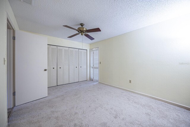 10037 62nd Ter N Unit 23, Saint Petersburg, FL 33708 - unfurnished bedroom with carpet floors, ceiling fan, a closet, and a textured ceiling
