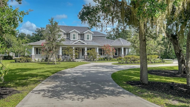 6050 Saddle Oak Trl, Sarasota, FL 34241 - view of front facade with a front lawn, curved driveway, a standing seam roof, a porch, and a metal roof