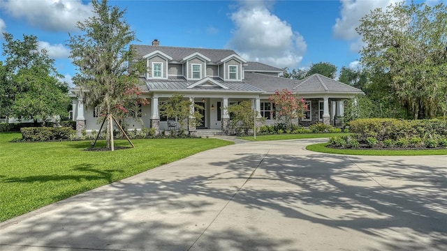 6050 Saddle Oak Trl, Sarasota, FL 34241 - view of front of house with covered porch, a standing seam roof, a front lawn, a chimney, and a metal roof