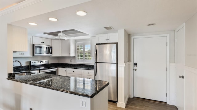 1257 S Portofino Dr Unit 306, Sarasota, FL 34242 - kitchen with appliances with stainless steel finishes, a peninsula, light wood-style flooring, dark stone counters, and white cabinets