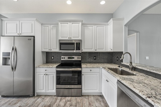 1042 Whitegate Ct, Sarasota, FL 34232 - kitchen featuring stainless steel appliances, white cabinetry, arched walkways, light wood-style flooring, and recessed lighting