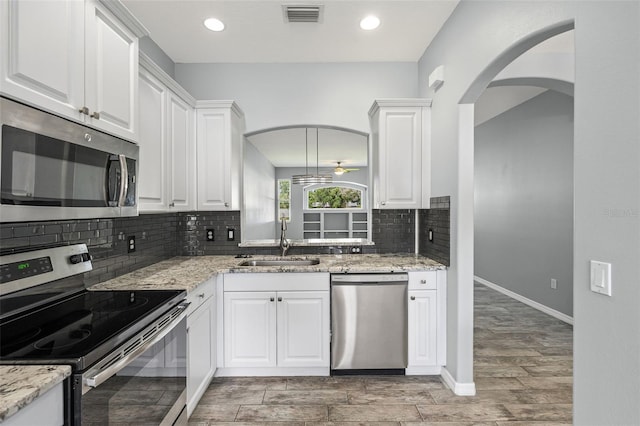 1042 Whitegate Ct, Sarasota, FL 34232 - kitchen featuring appliances with stainless steel finishes, backsplash, wood tiled floors, white cabinets, and recessed lighting