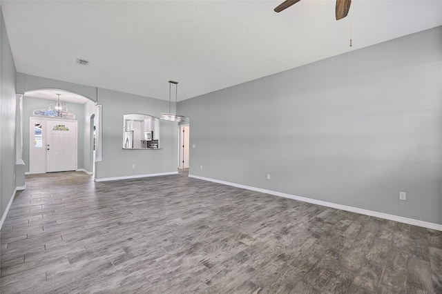 1042 Whitegate Ct, Sarasota, FL 34232 - unfurnished living room featuring arched walkways, wood finished floors, a ceiling fan, and a chandelier
