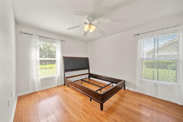 7115 39th Ln E, Sarasota, FL 34243 - bedroom with light wood-style flooring, a textured ceiling, and a ceiling fan