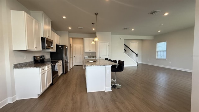 14312 Crimson Ave, Bradenton, FL 34211 - kitchen featuring appliances with stainless steel finishes, dark wood-type flooring, white cabinets, a kitchen bar, and an island with sink
