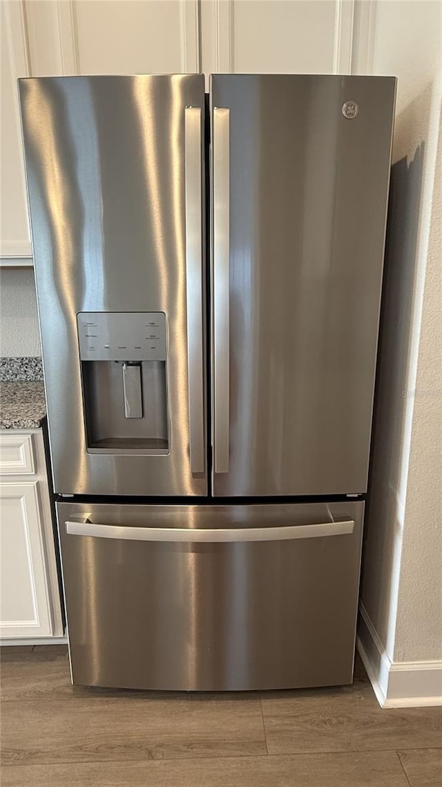 14312 Crimson Ave, Bradenton, FL 34211 - detailed view of stainless steel refrigerator with ice dispenser, light wood finished floors, white cabinets, and light stone countertops