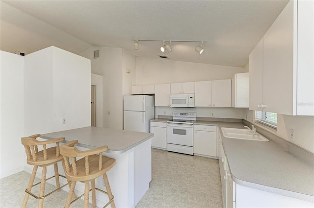 7824 48th Pl E, Bradenton, FL 34203 - kitchen with white appliances, lofted ceiling, a peninsula, rail lighting, and white cabinetry