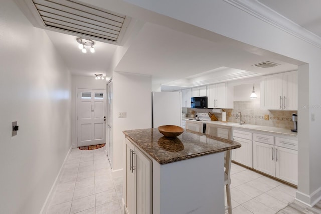4414 Mount Vernon Dr Unit 1, Bradenton, FL 34210 - kitchen featuring white appliances, light tile patterned floors, white cabinets, and a kitchen island