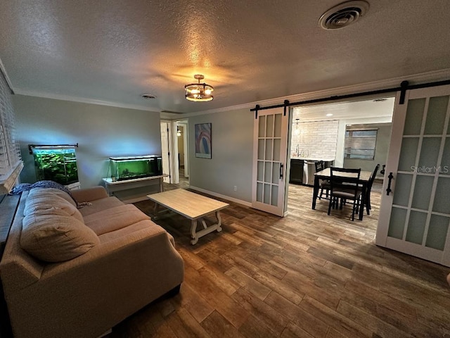 611 Missouri Rd, Venice, FL 34293 - living area with a barn door, a textured ceiling, ornamental molding, and wood finished floors