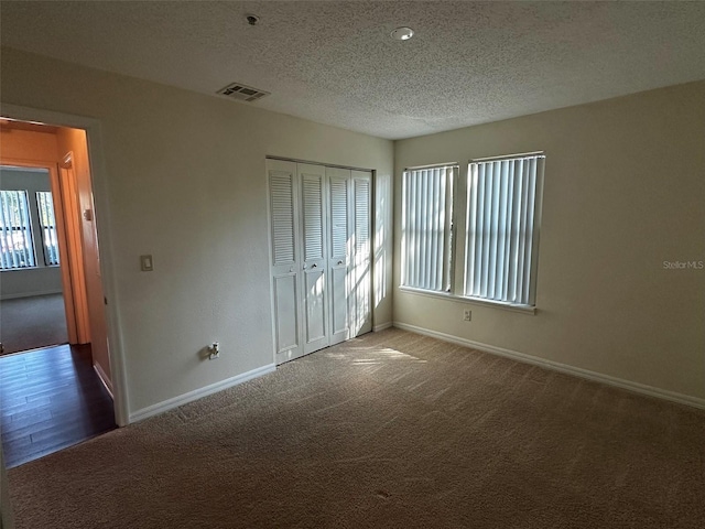 4002 Crockers Lake Blvd Unit 11, Sarasota, FL 34238 - unfurnished bedroom featuring multiple windows, a textured ceiling, carpet, and a closet