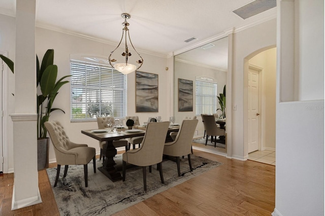 12113 Whistling Way, Lakewood Ranch, FL 34202 - dining space featuring arched walkways, wood finished floors, and crown molding