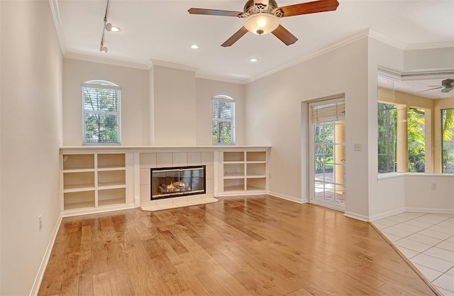 12113 Whistling Way, Lakewood Ranch, FL 34202 - unfurnished living room featuring ceiling fan, wood finished floors, healthy amount of natural light, a tile fireplace, and ornamental molding