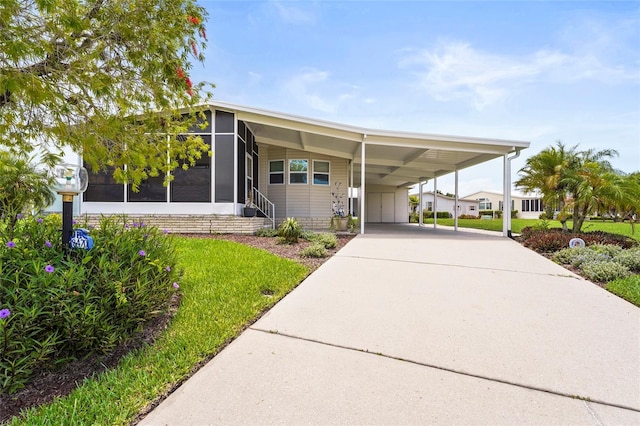 8470 Imperial Cir, Palmetto, FL 34221 - manufactured / mobile home featuring a sunroom, driveway, an attached carport, and a front yard