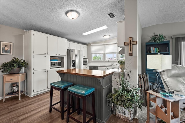 8470 Imperial Cir, Palmetto, FL 34221 - kitchen with appliances with stainless steel finishes, butcher block counters, vaulted ceiling, wood finished floors, and a textured ceiling