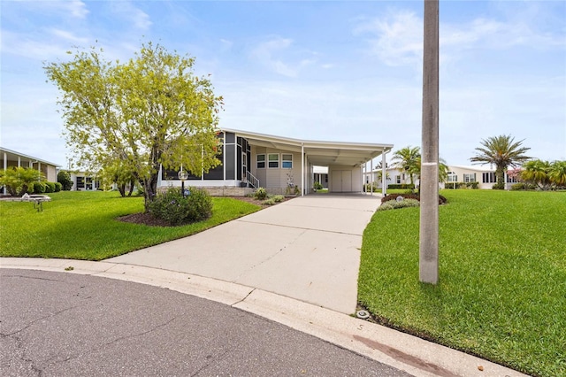 8470 Imperial Cir, Palmetto, FL 34221 - manufactured / mobile home with driveway, a front lawn, a sunroom, and an attached carport